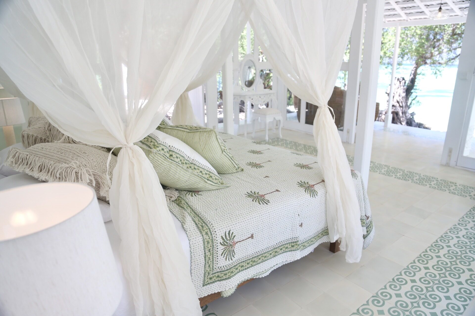 A canopied daybed draped in white linen open to the turquoise lagoon